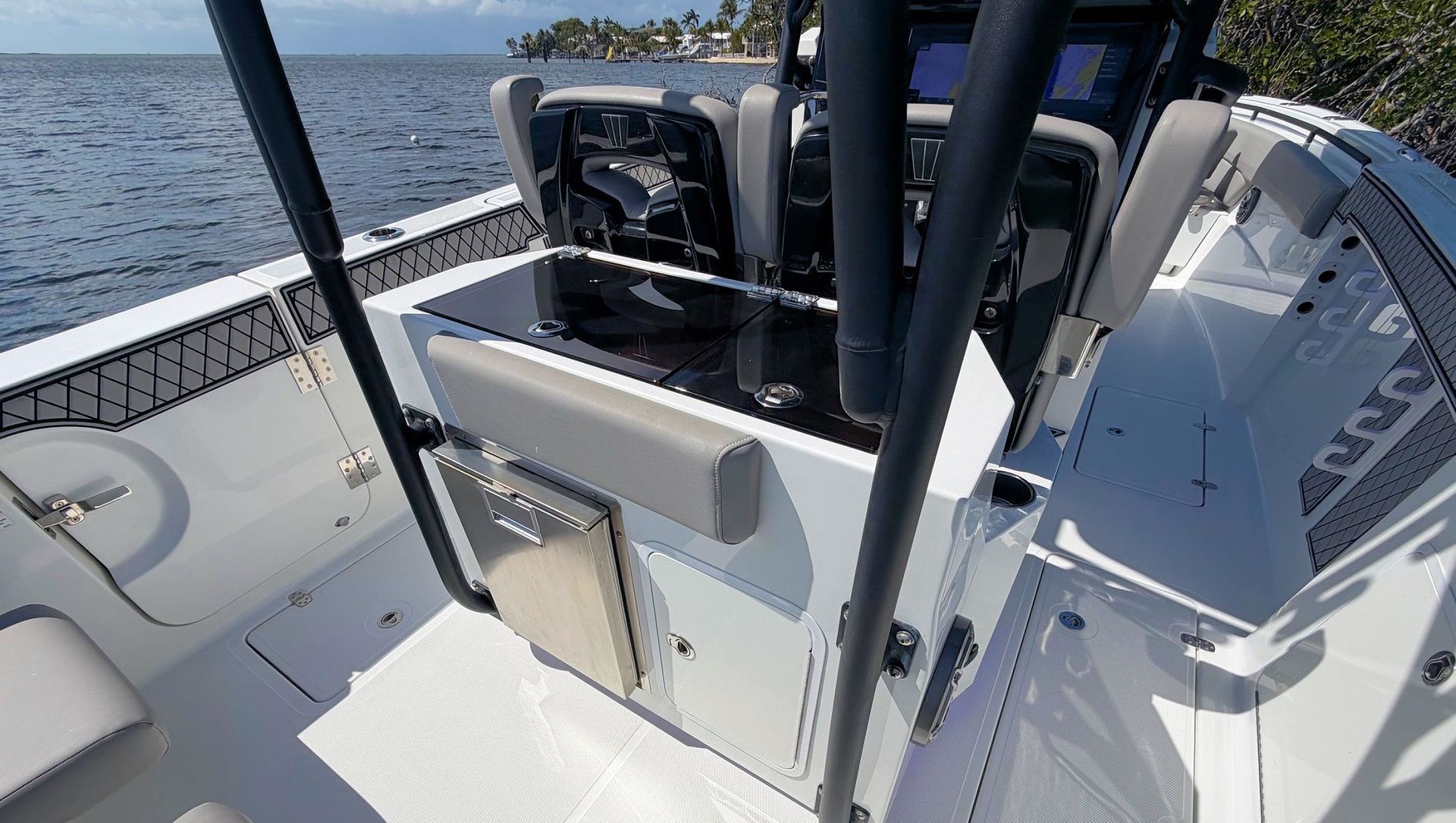 Boating cockpit with white deck, black railings, and open water beside the vessel