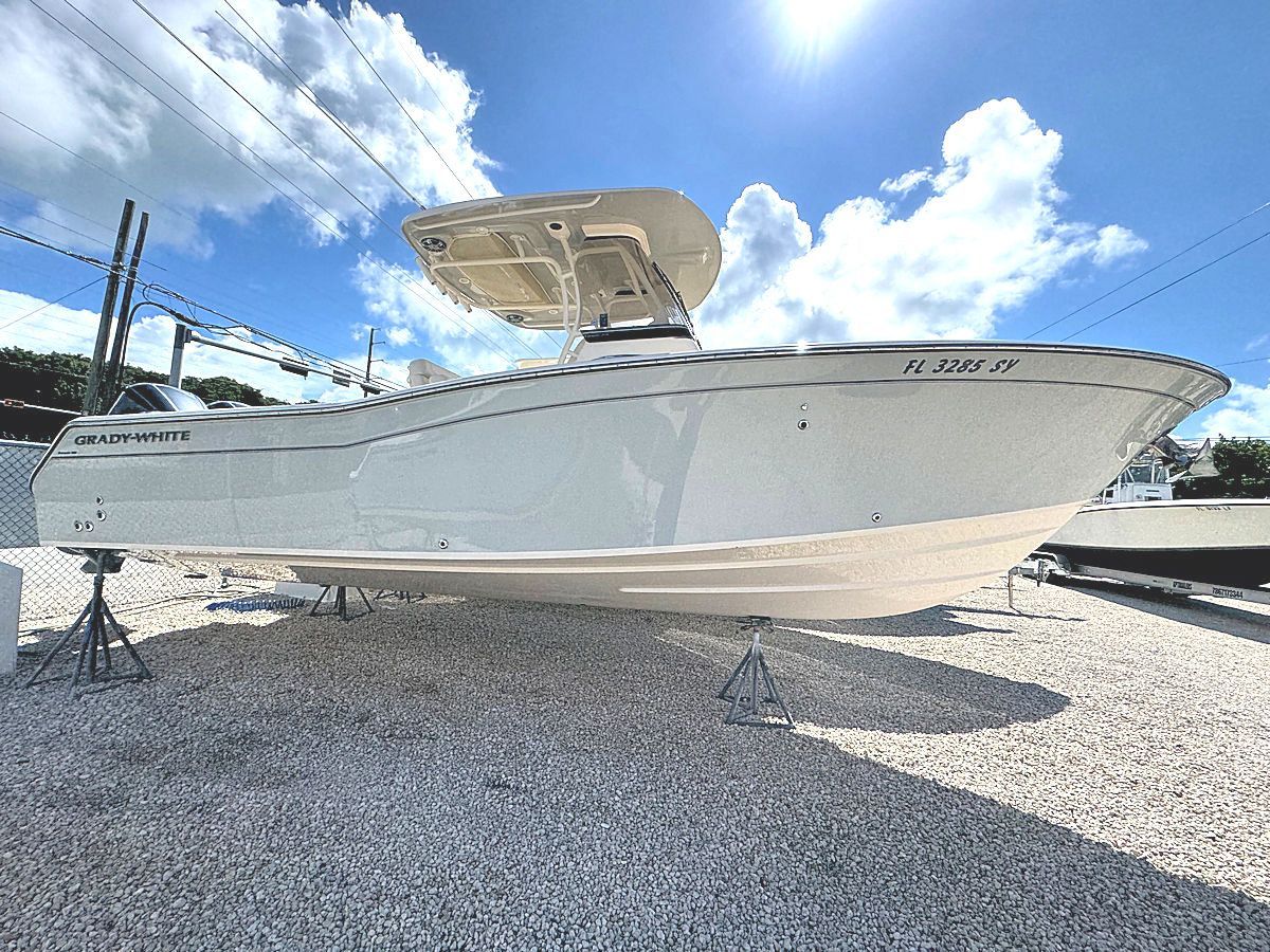 White boat on a gravel lot under a bright, sunny sky.