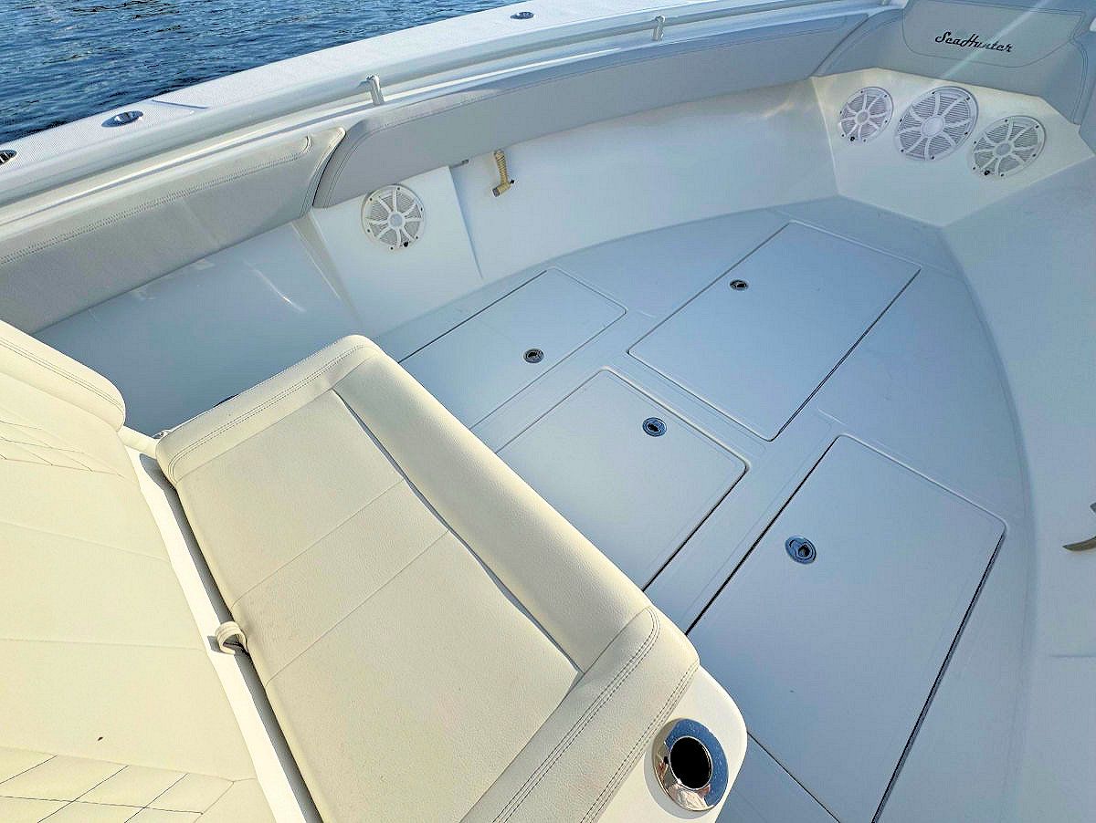 Interior of a white boat with padded seating, storage compartments, and speakers.