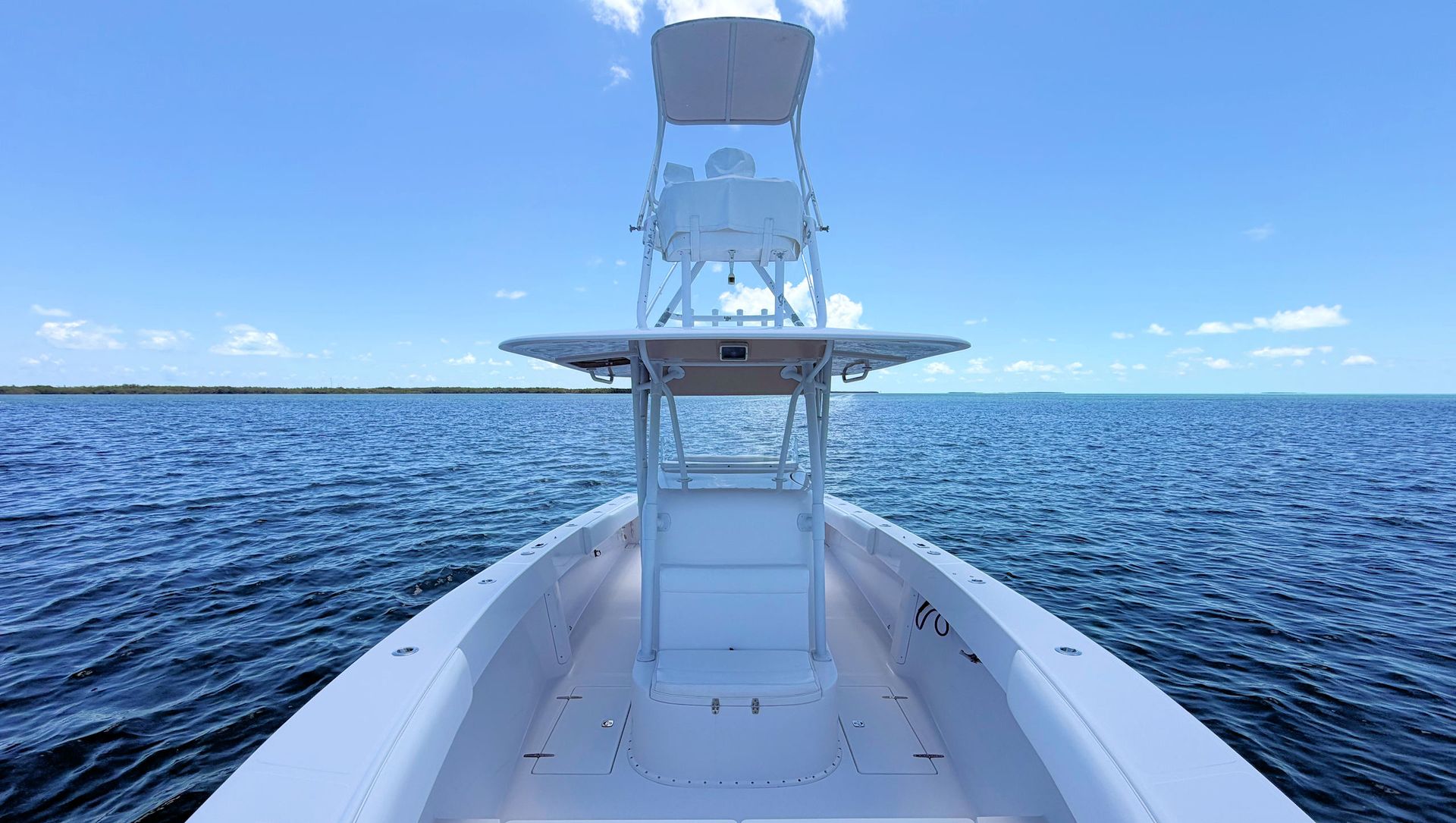Facing aft towards the center console,  t-top and upper helm station on the  open ocean under a clear blue sky