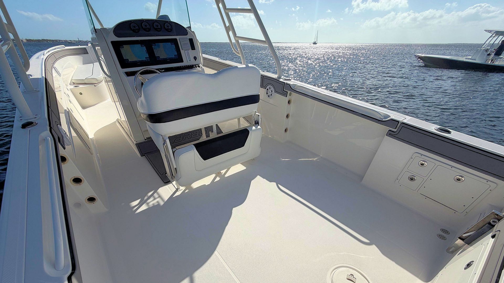 Boat deck with white seating and helm, overlooking a sunny open ocean.