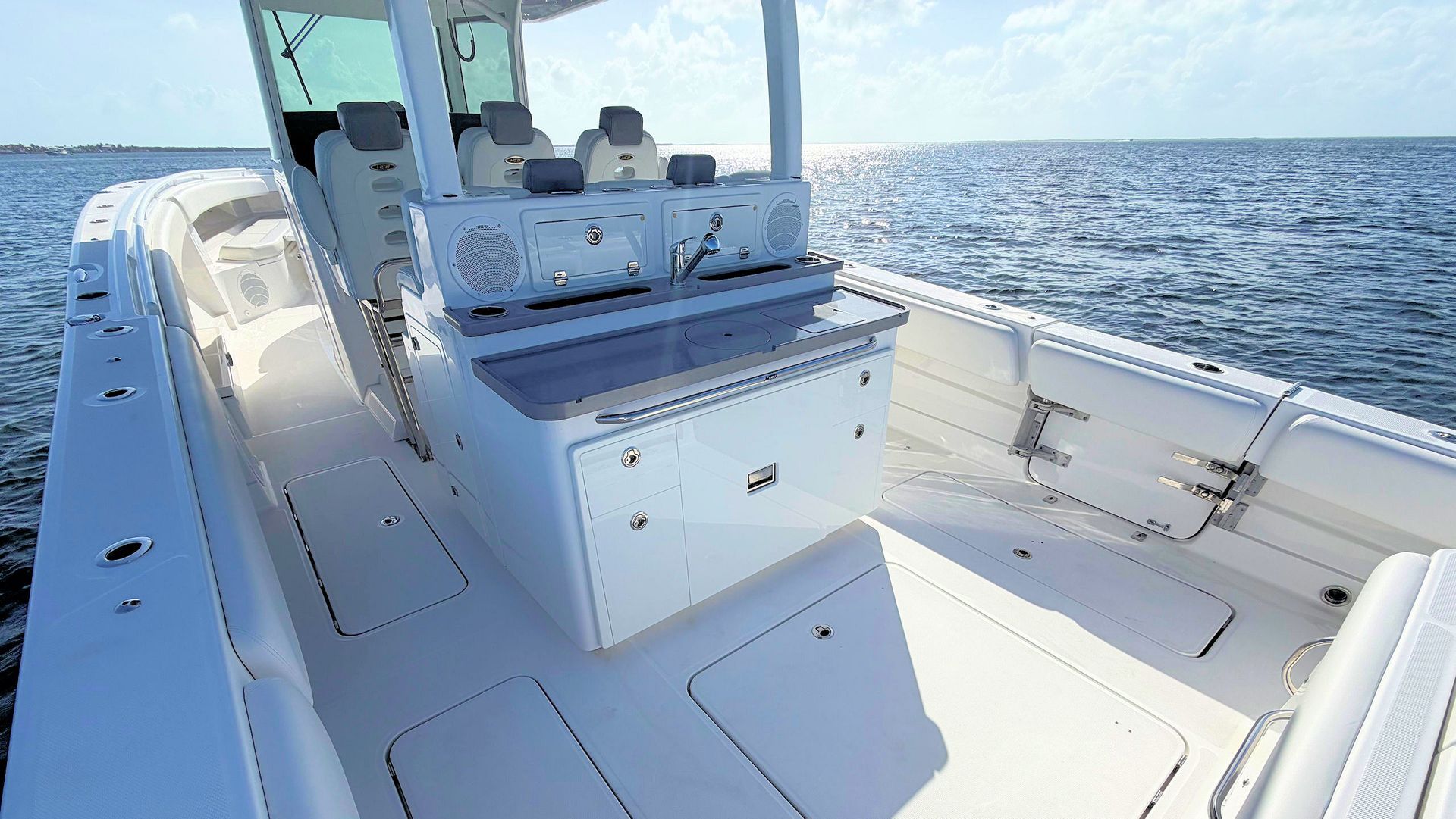 White fishing boat deck with center console cruising on open blue water under a clear sky