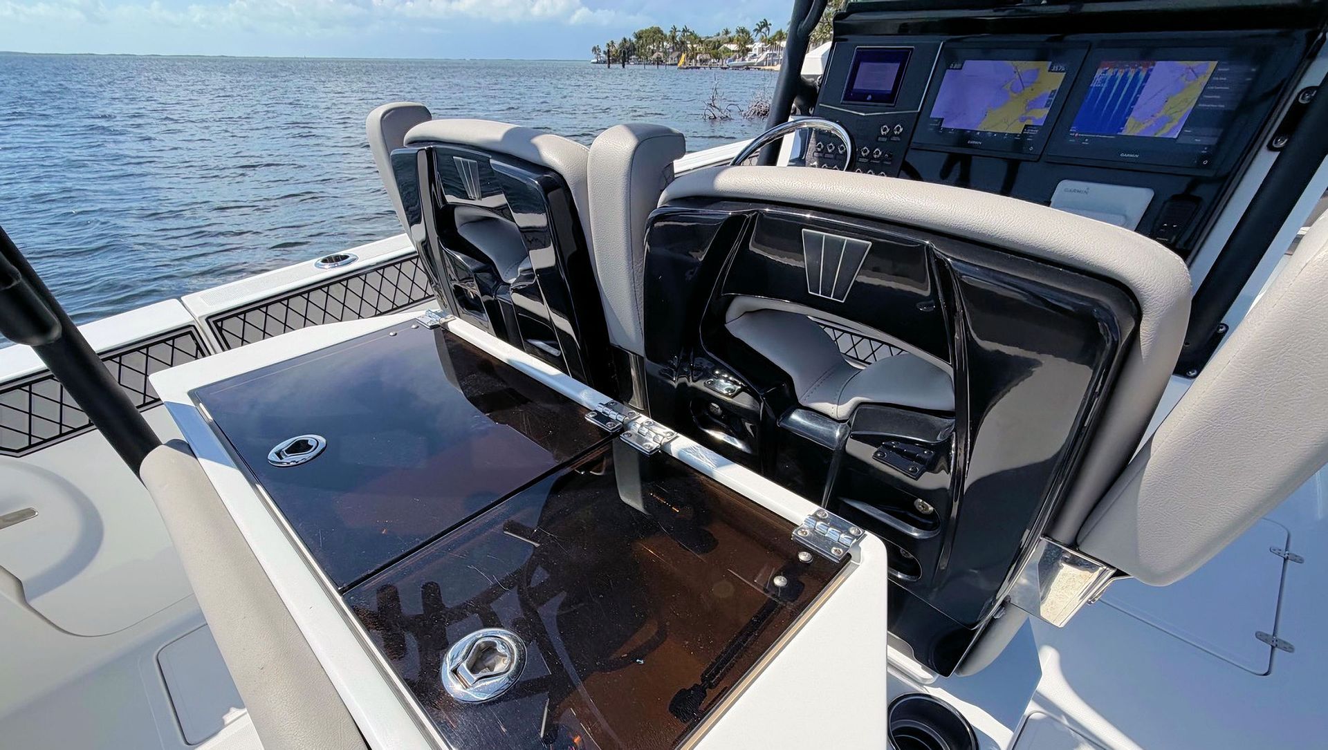 Cockpit of a boat with black seats and digital screens on the water