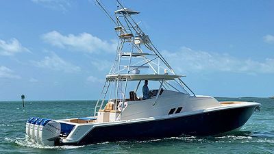 Blue and white fishing boat on water with tall tower, under a blue sky.