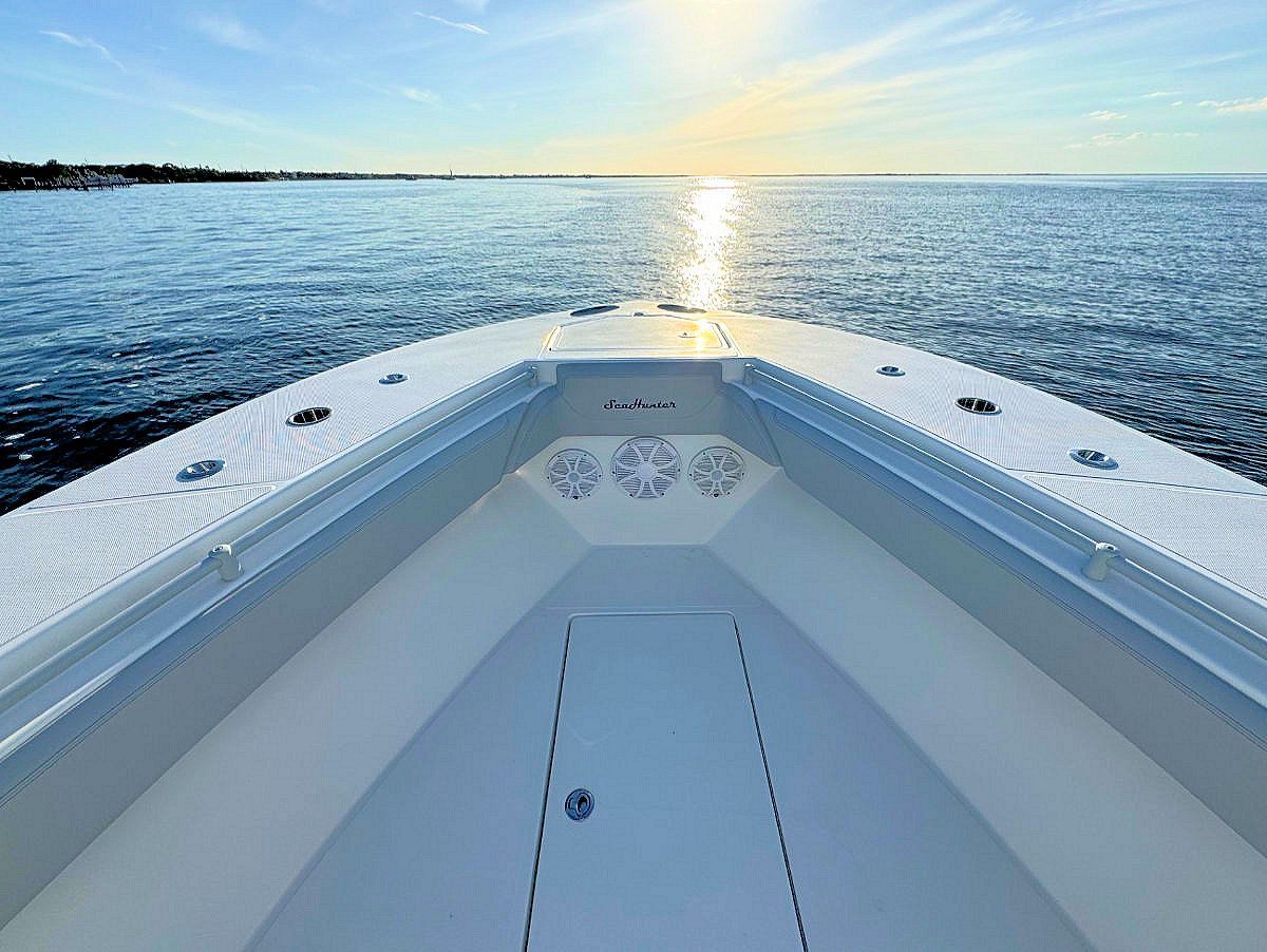 Boat bow on water, sunlit horizon, blue water, white boat interior.