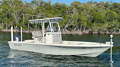 Gray fishing boat on water near trees.