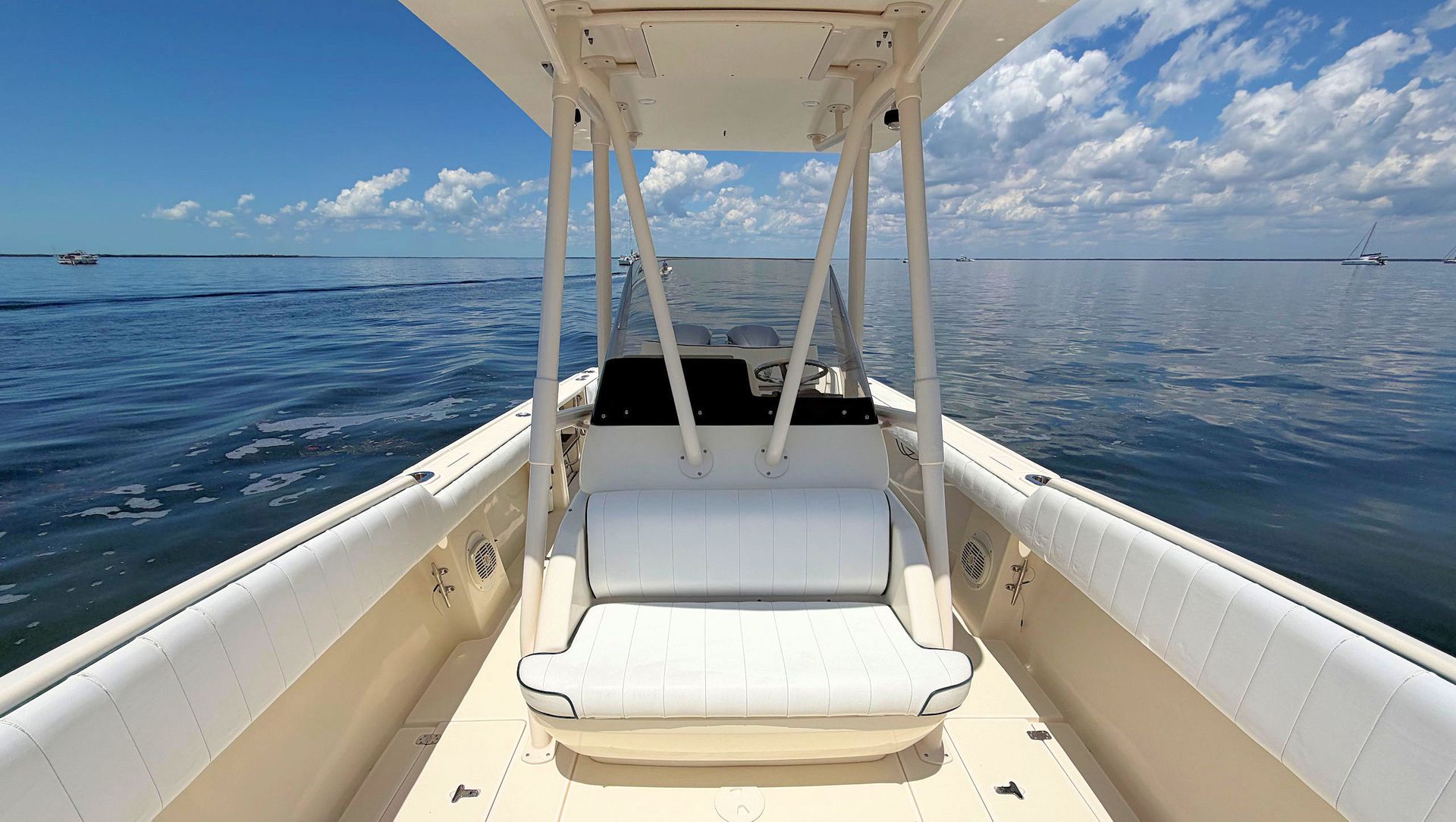 View from the bow looking aft at boat’s center console over calm blue water under a bright sky