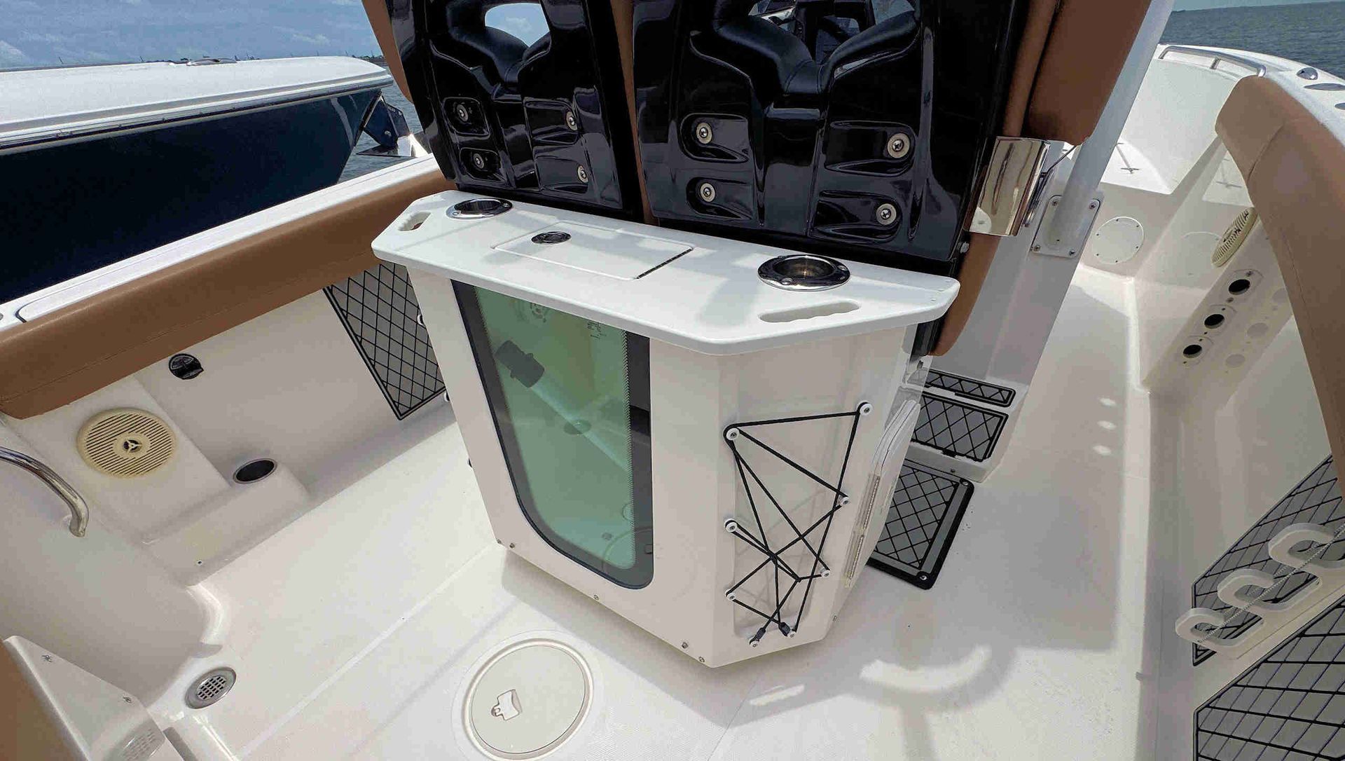 Boat cockpit with open hatch showing a built-in cooler and storage compartments.