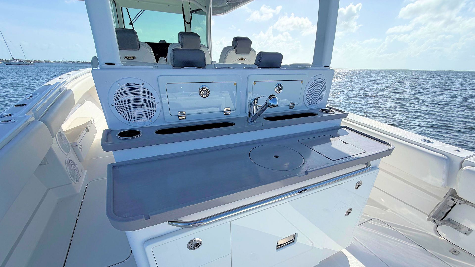 Boat stern with built-in bait station and cooler on a white fishing boat, ocean and sky in the background