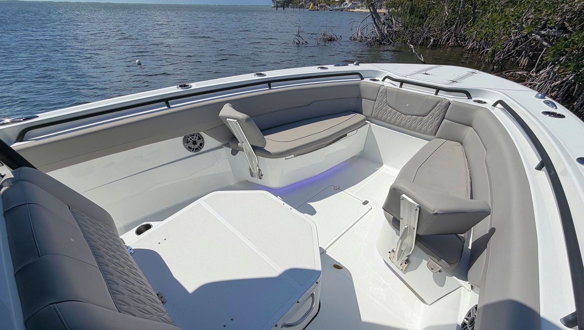 White boat cockpit with gray seating and a small table on the water