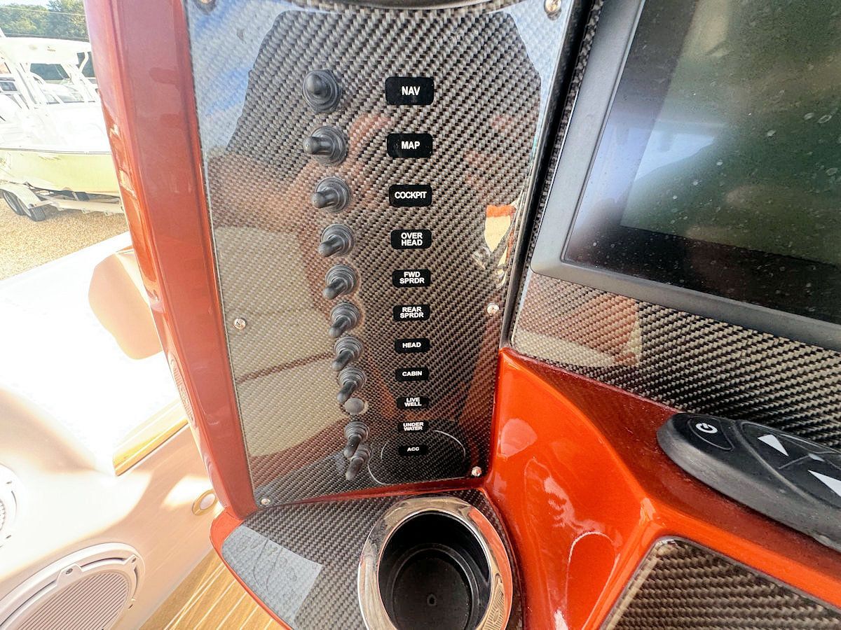 Dashboard with buttons, carbon fiber panel, and cup holder on a boat.