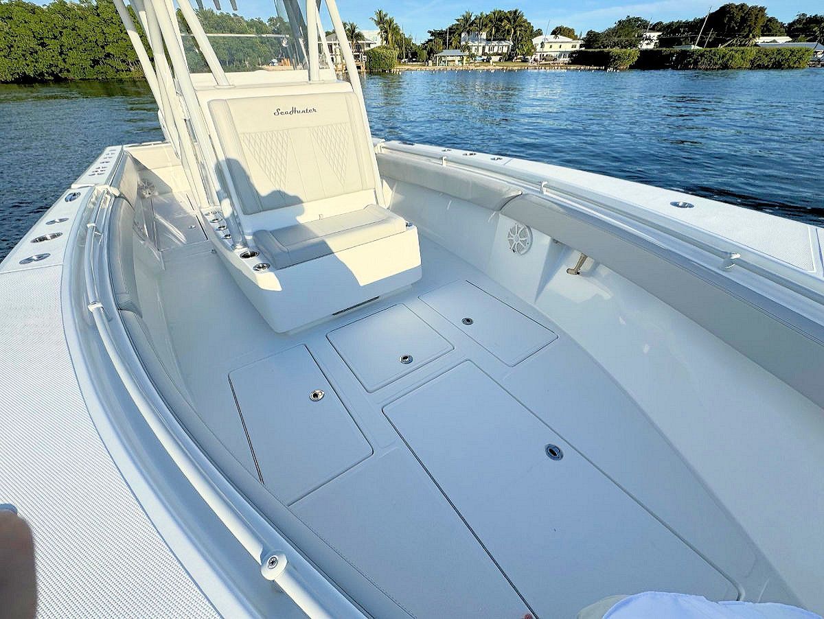 White boat deck with open storage compartments, blue water background.