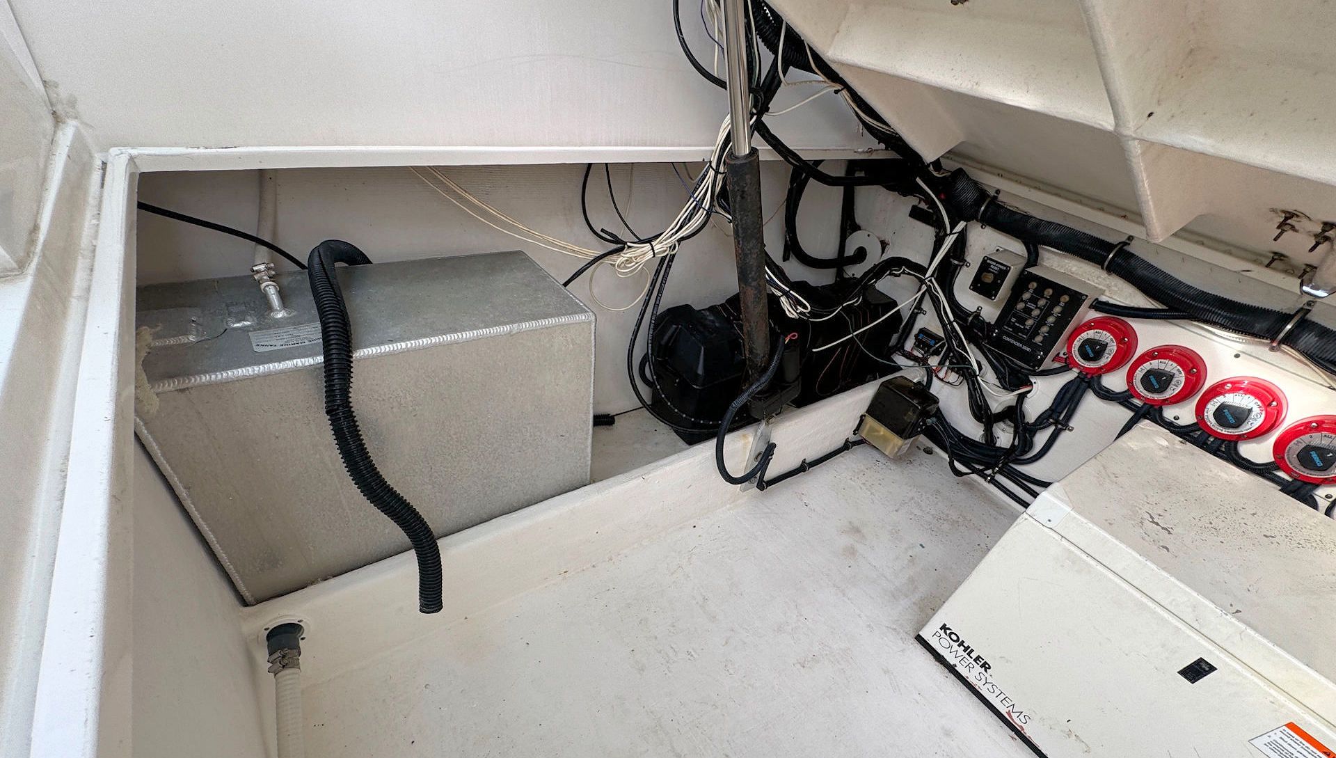 Small boat storage compartment with gray box, tangled cables, and red-ringed connectors along the right wall