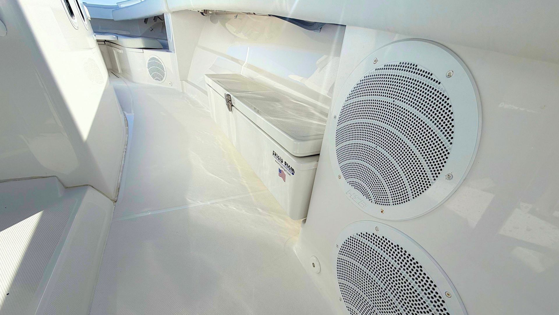 White boat cabin interior with cushioned seating and two round speaker or vent grilles on the wall
