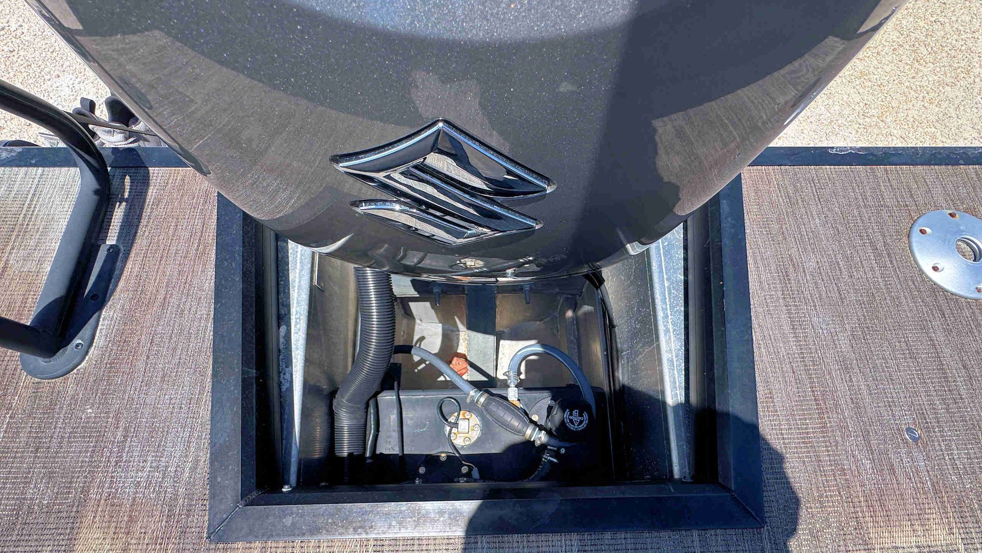 Close-up of a boat engine compartment with exposed machinery in a metal hatch.