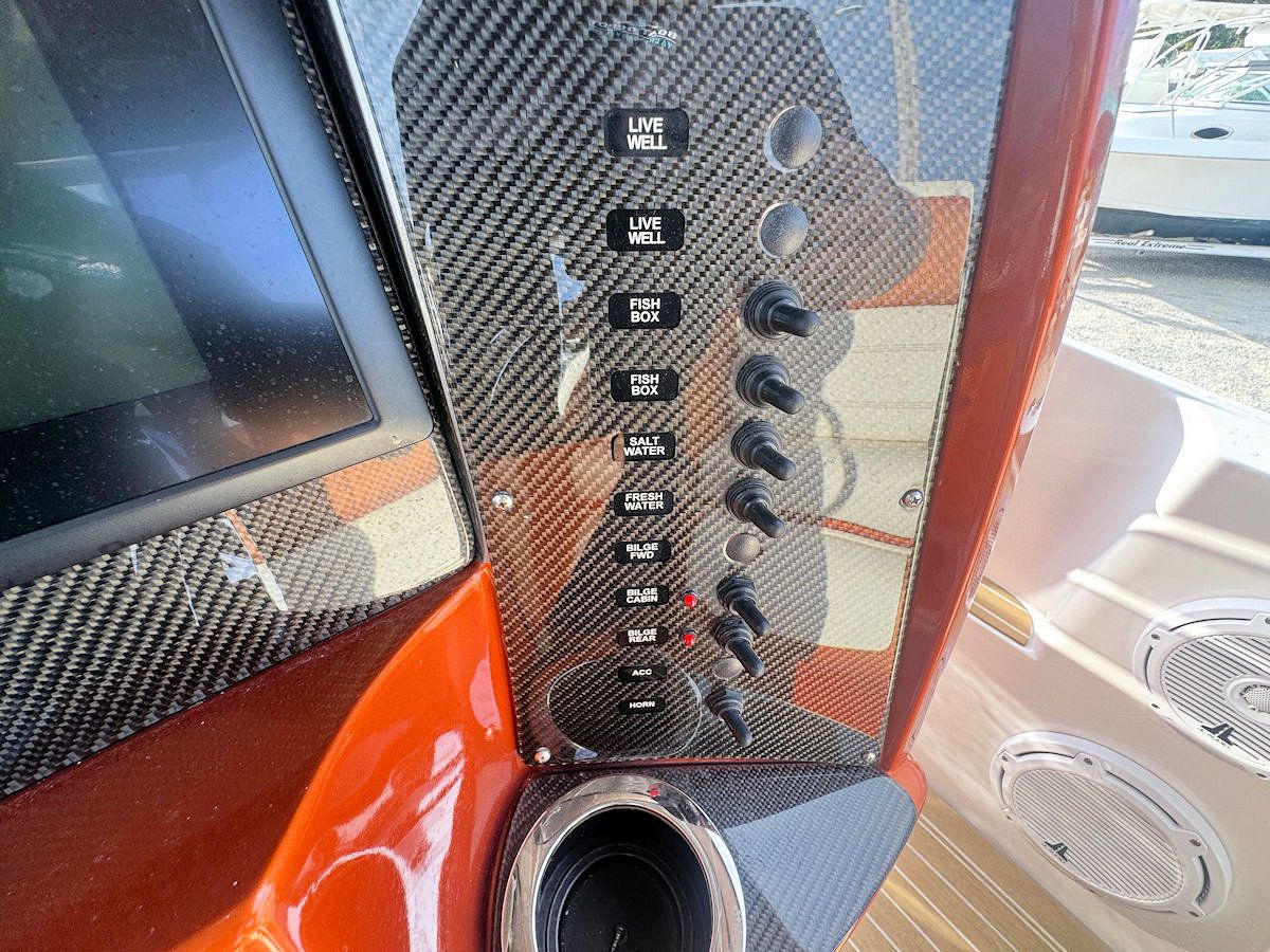 Boat dashboard with carbon fiber, multiple switches, and a cup holder.