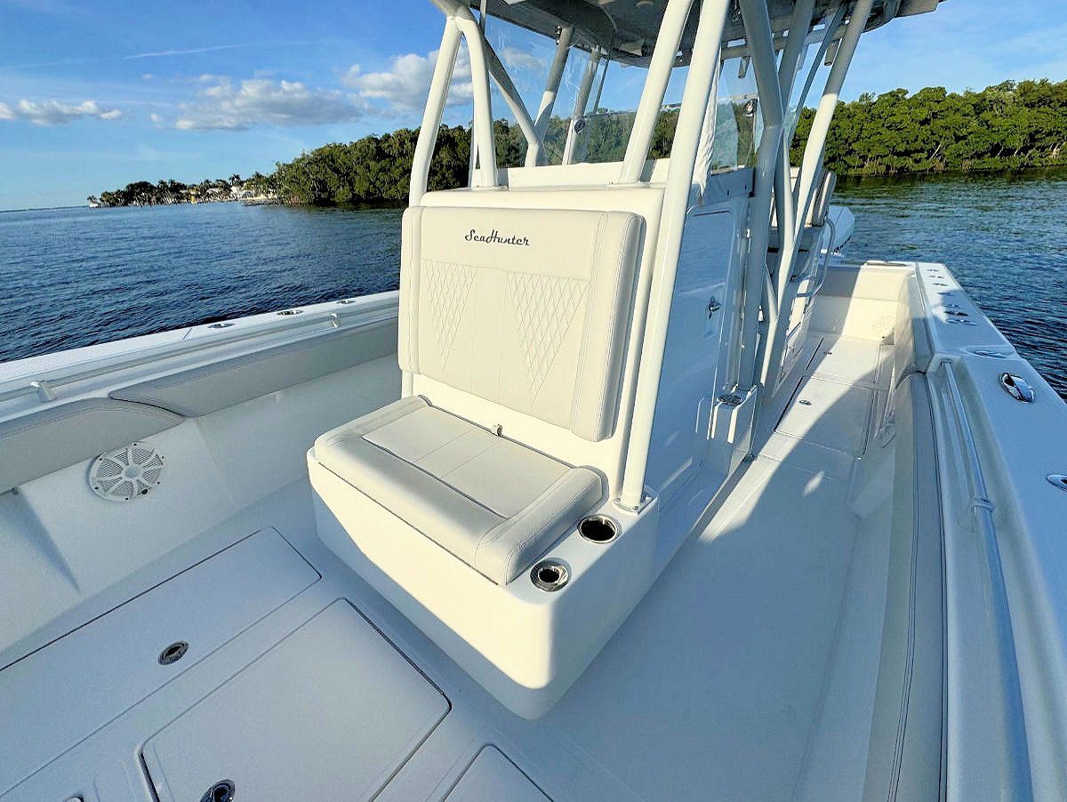 White center console boat on water. Interior view shows helm seat, windshield, and surrounding deck.