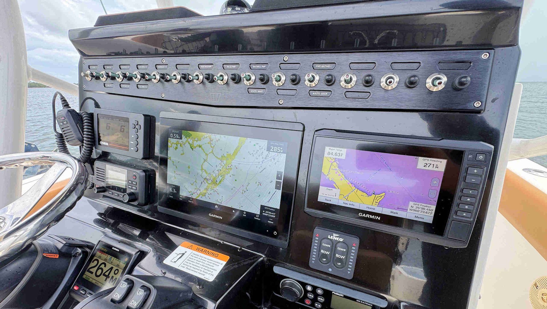 Helm with multiple navigation displays and control panels mounted on a black dashboard.