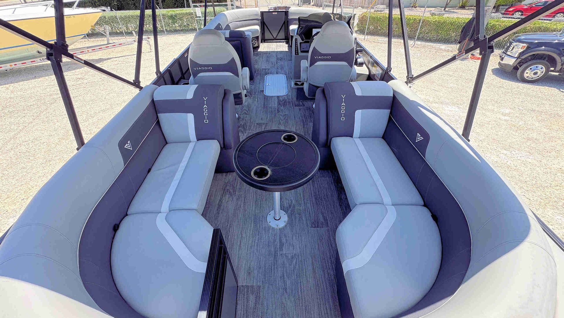 Gray upholstered boat interior with two front seats and a central black console under a canopy.