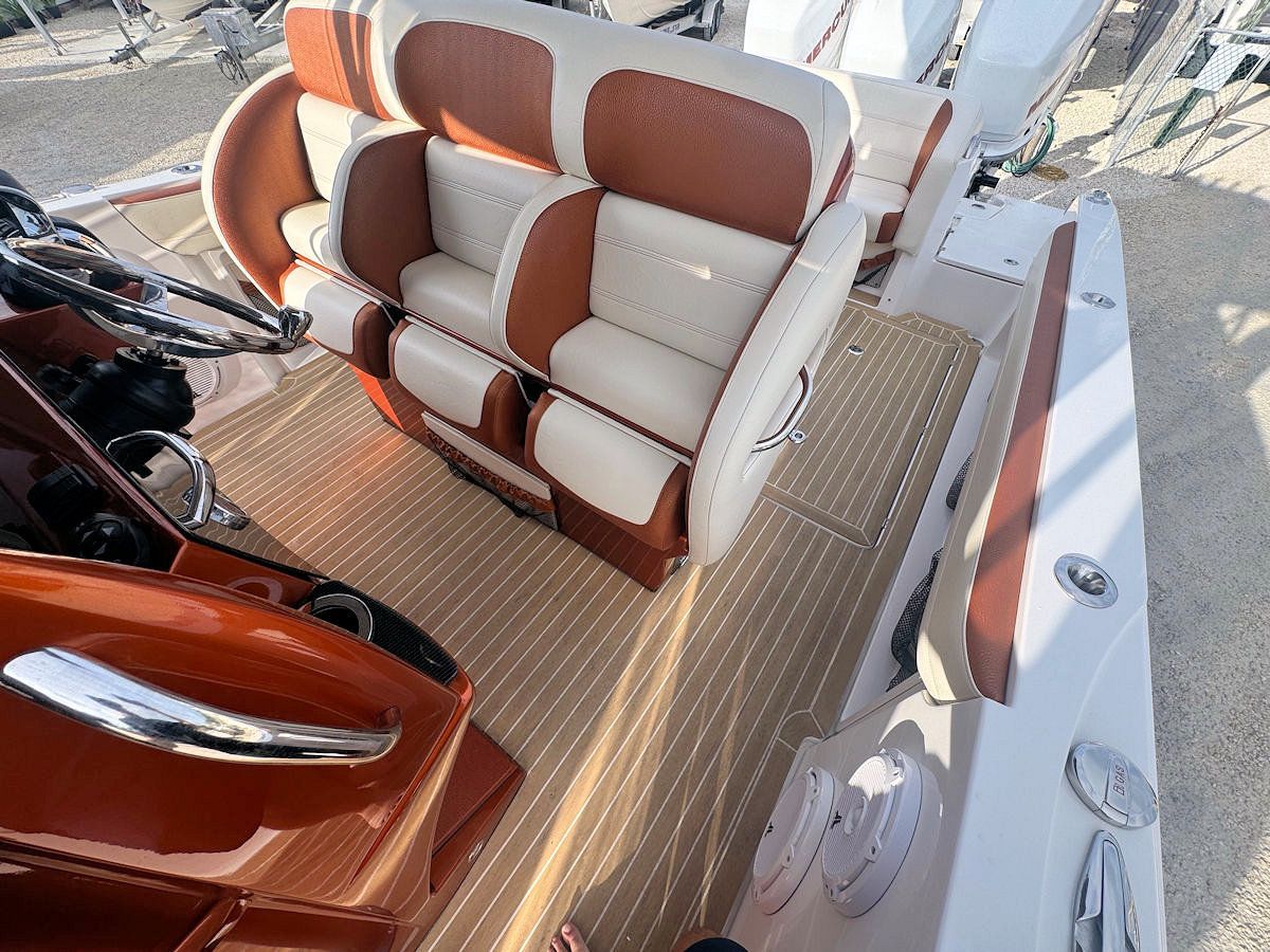 Boat interior with brown and white leather seating, wood-grain flooring, and a dashboard.