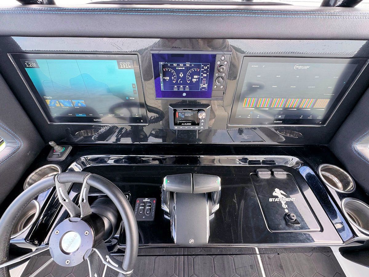Boat dashboard with navigation screens, steering wheel, and controls.