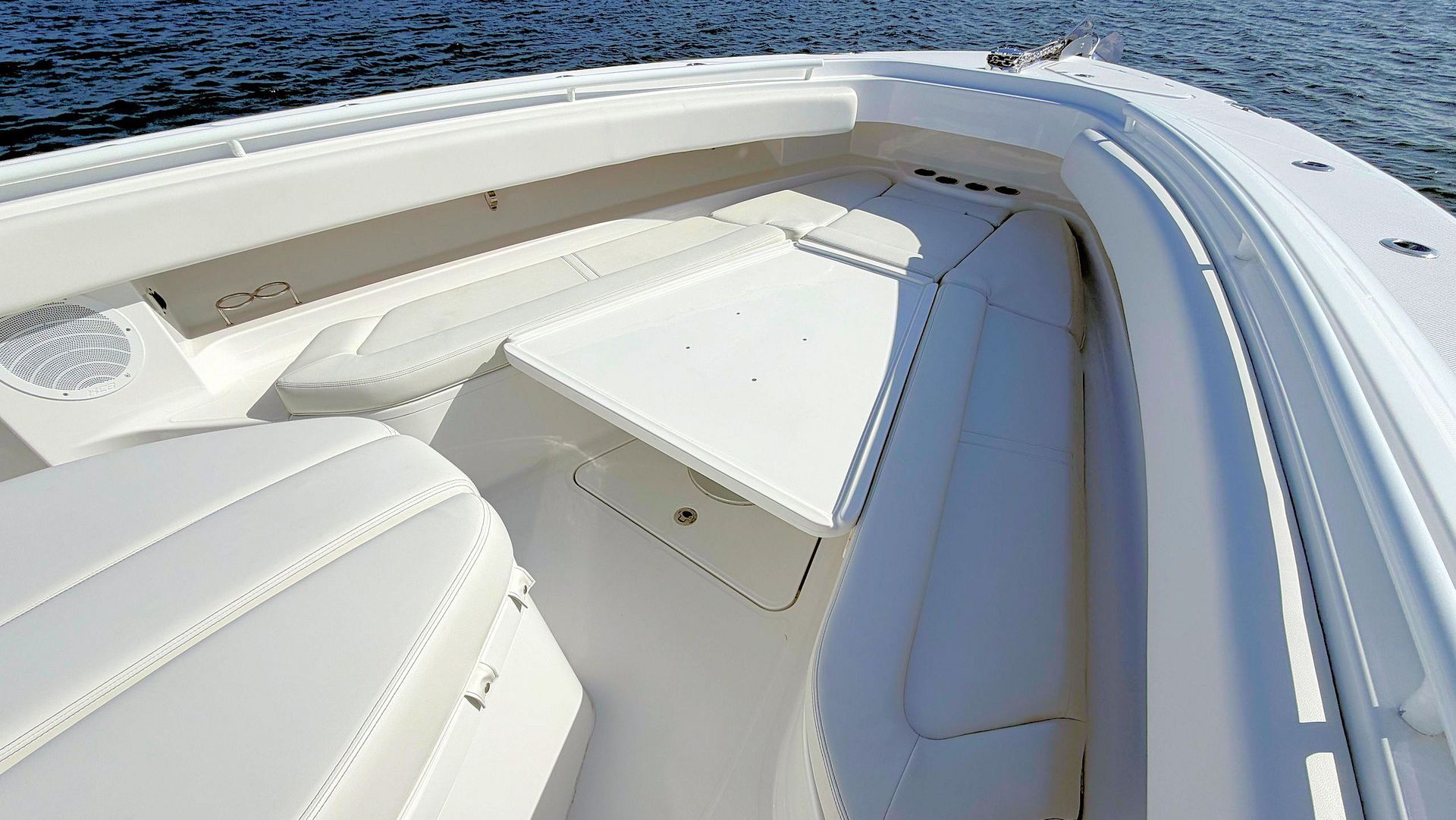 Bow of boat with cushioned seating and curved windshield on a sunny day