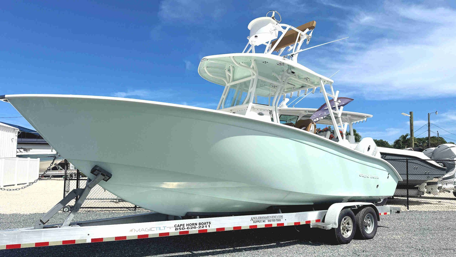Light green Cape Horn center-console boat on a trailer at a boat yard under a blue sky