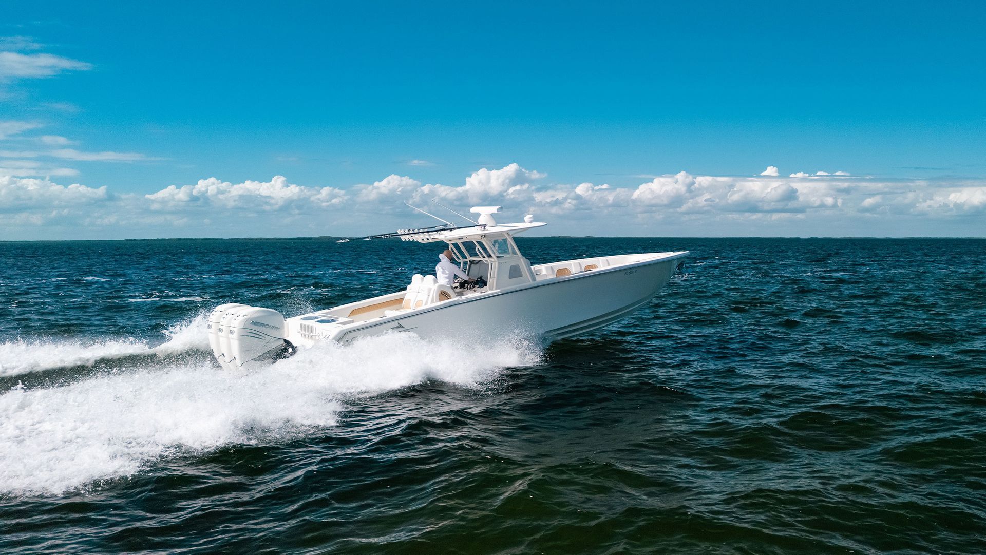 White speedboat cutting through choppy blue water under a cloudy sky