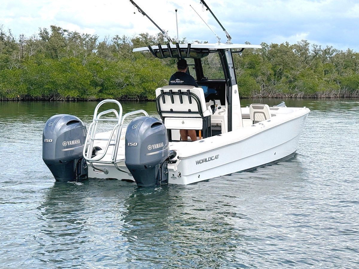 White fishing boat with two outboard motors in the water near mangroves, person at helm.
