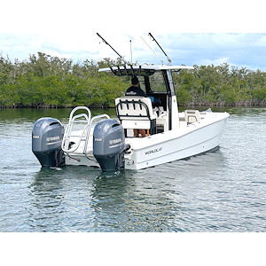 White speedboat on calm water with blue sky and light foliage in the background.