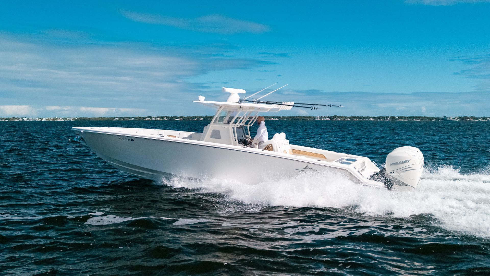 White center-console speedboat racing across choppy blue water under a clear sky