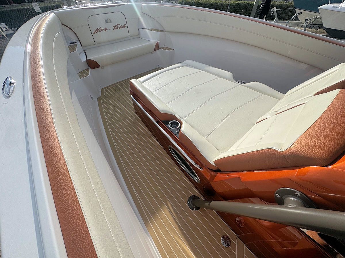 Interior view of an orange and white boat with beige seating and wooden flooring.