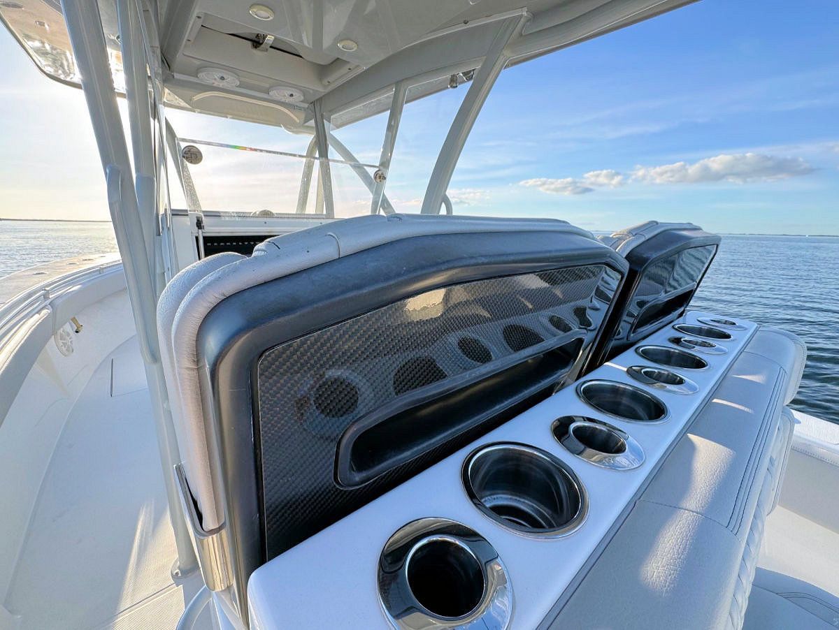 White motorboat with cushioned seats, cup holders, and a blue sky in the background.