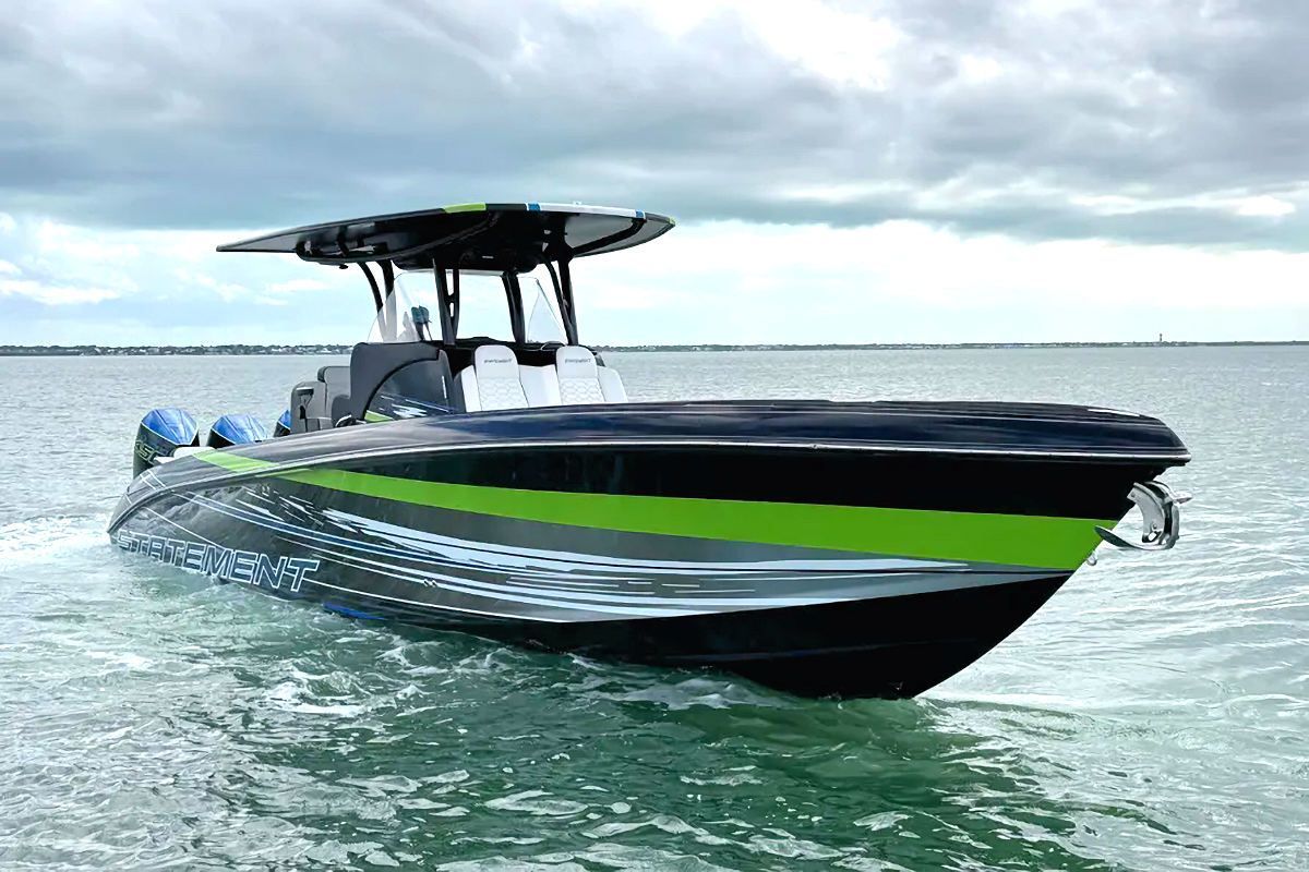 Black and green powerboat on the water under a cloudy sky.