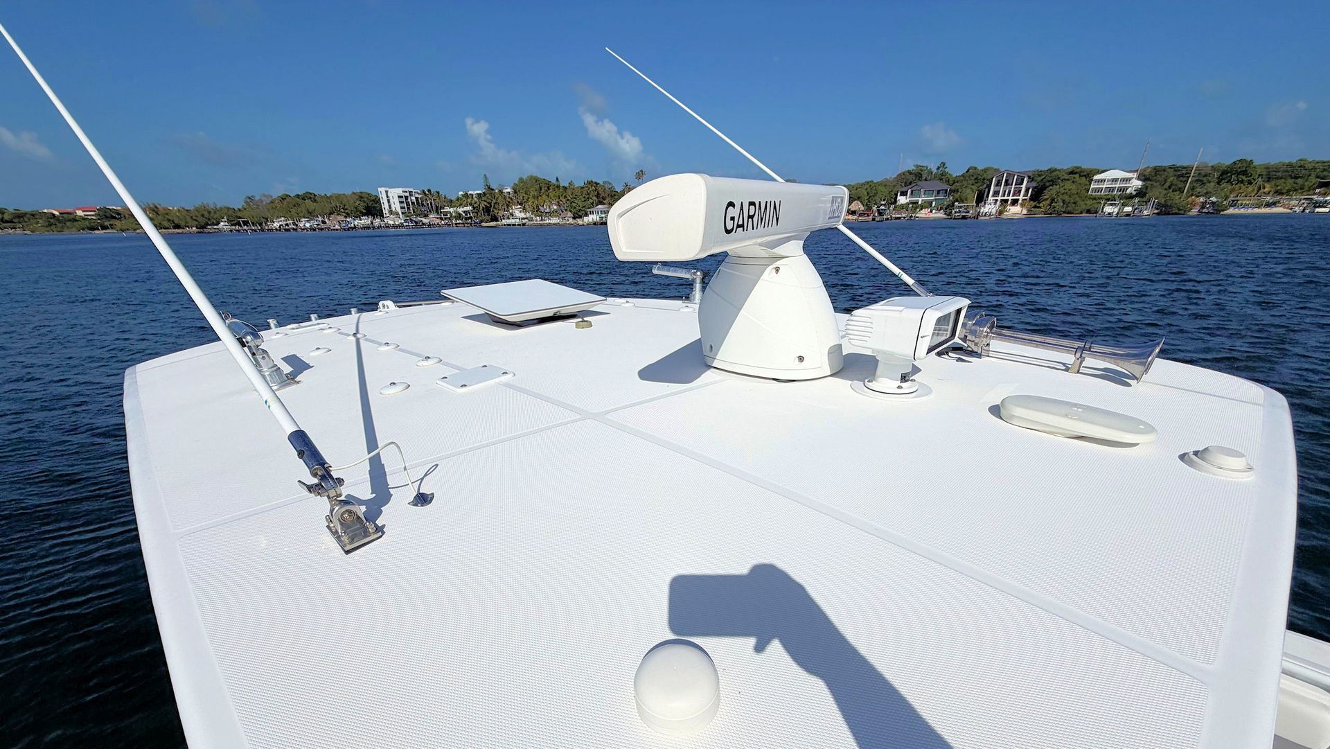 View of top of hard top with radar dome and antennas on blue water under a clear sky