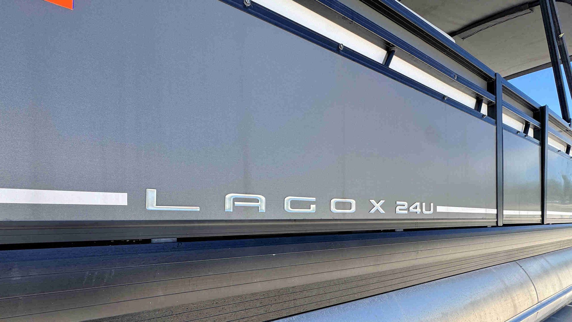 Close-up of a gray side panel with white lettering reading “LAGO x24U” under a blue sky