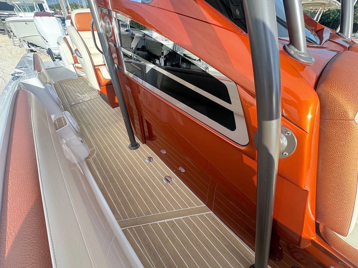 Orange and brown boat deck with a side view of cabin windows and metal railings.
