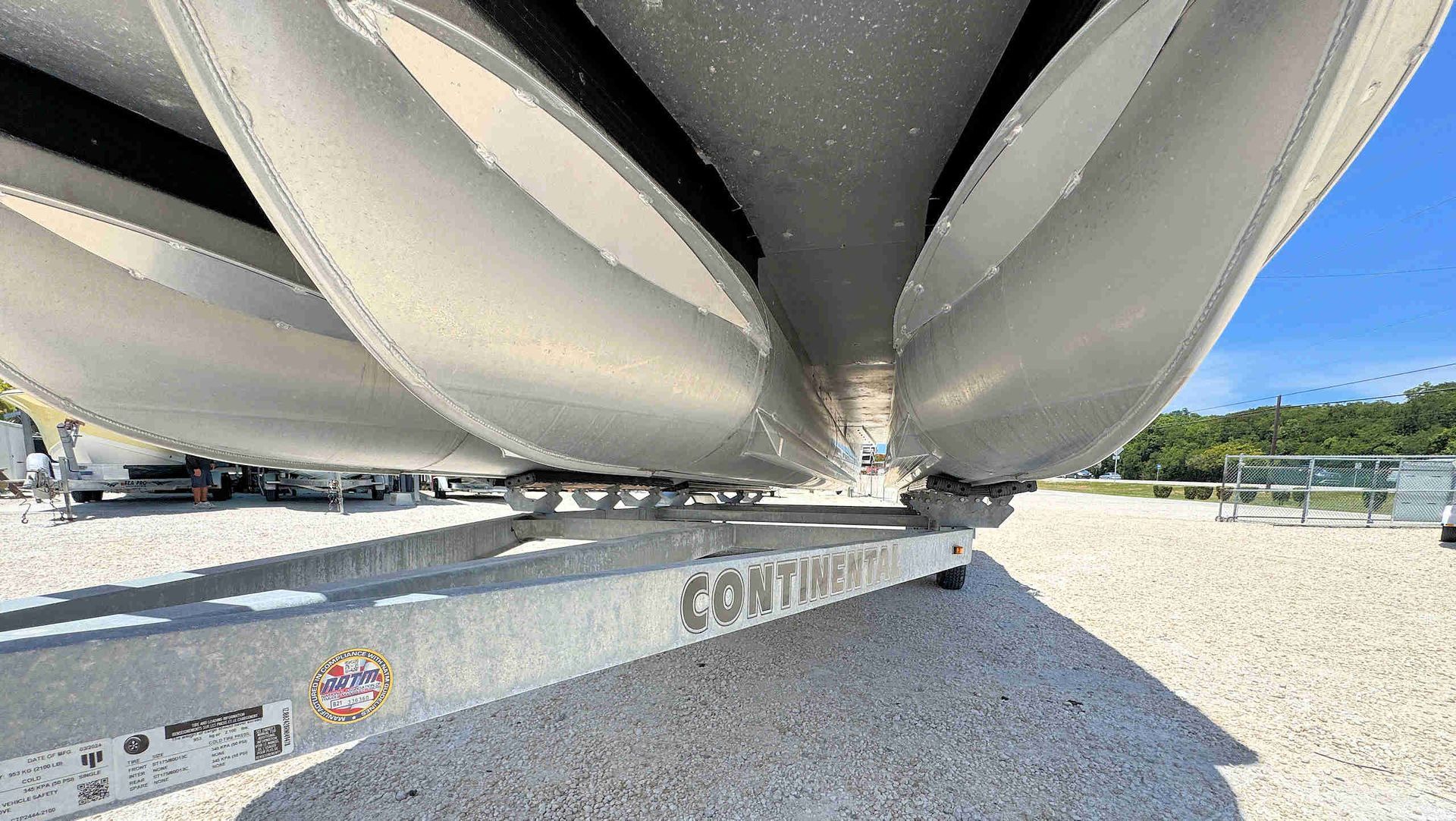 Close-up of a large gray metal structure under a blue sky on gravel, with a visible 