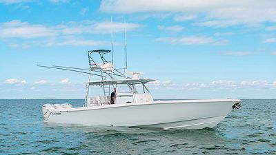 White motorboat on ocean with blue sky and light clouds.