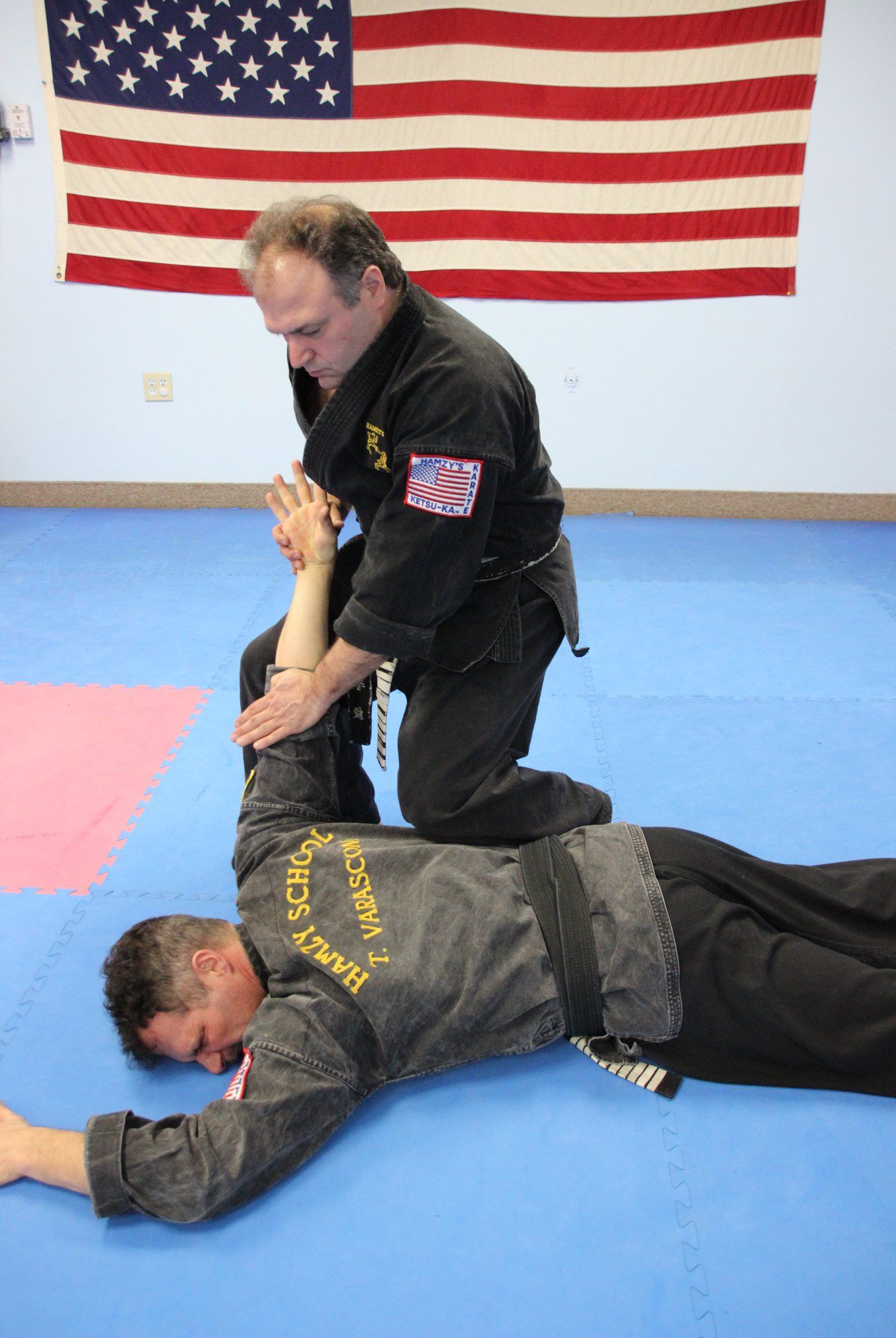 Two men are practicing martial arts in front of an american flag.
