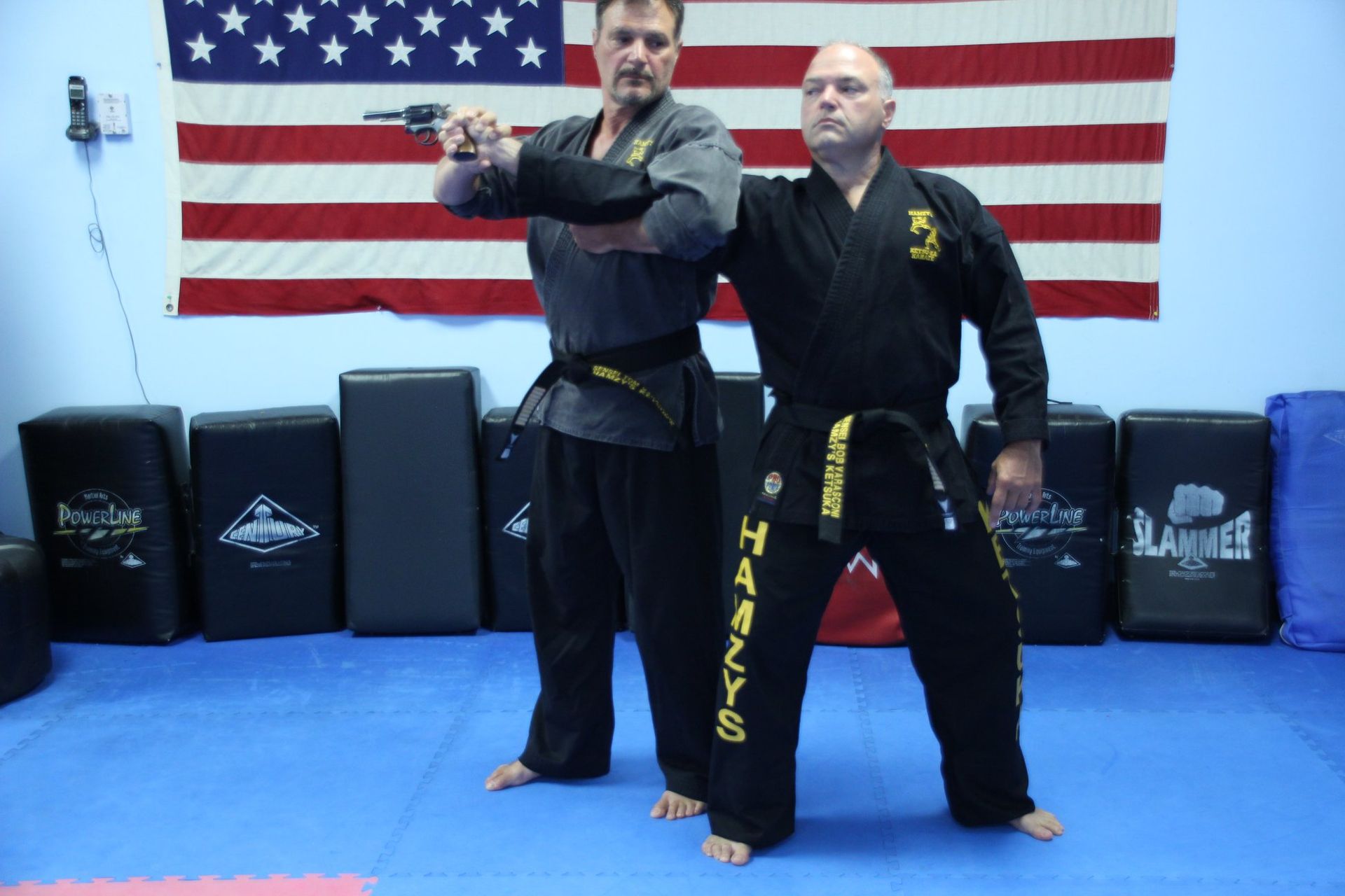 Two men in karate uniforms standing in front of an american flag