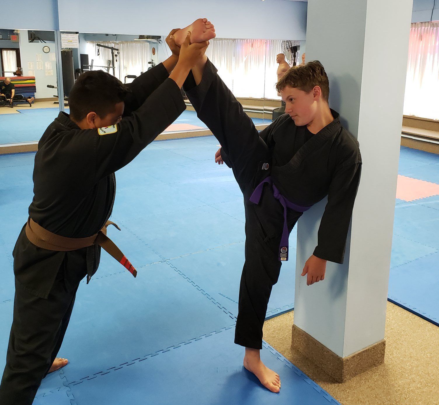 Two young men are practicing martial arts in a gym