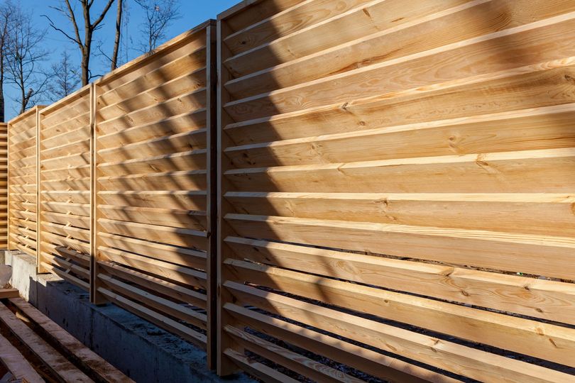 Wooden horizontal slat fence in sunlight.