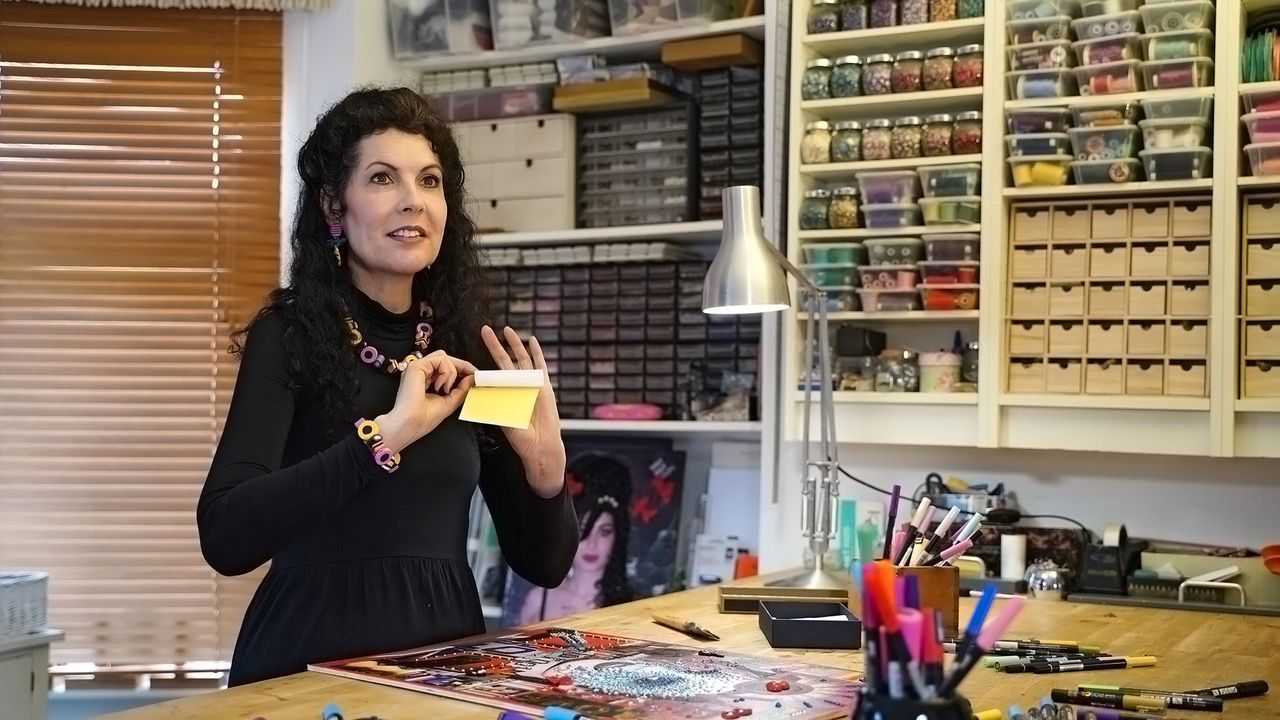 Red vase with gold tree branches, blue leaves, white birds, and floral details on a black background.