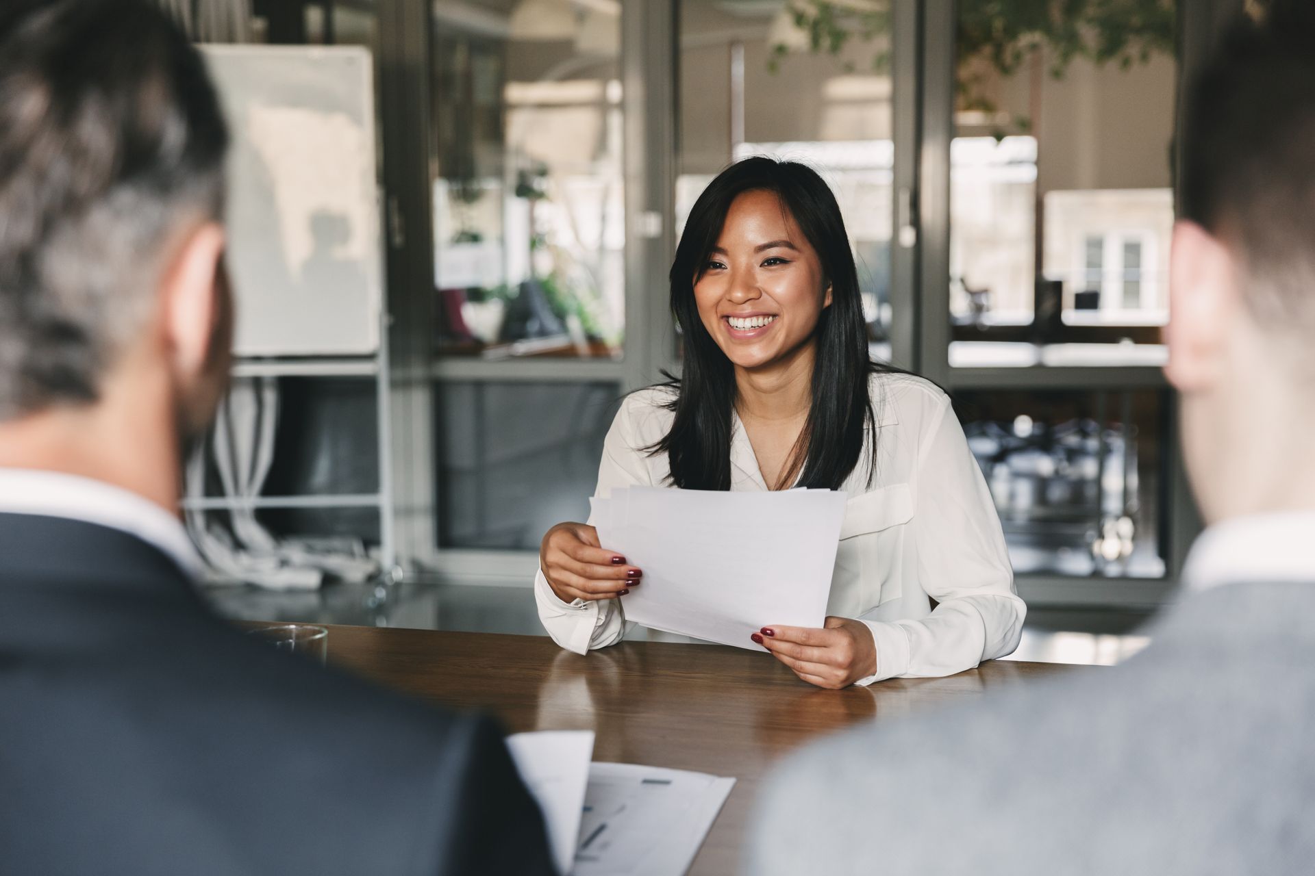 A woman is sitting at a table holding a piece of paper during a job interview.
