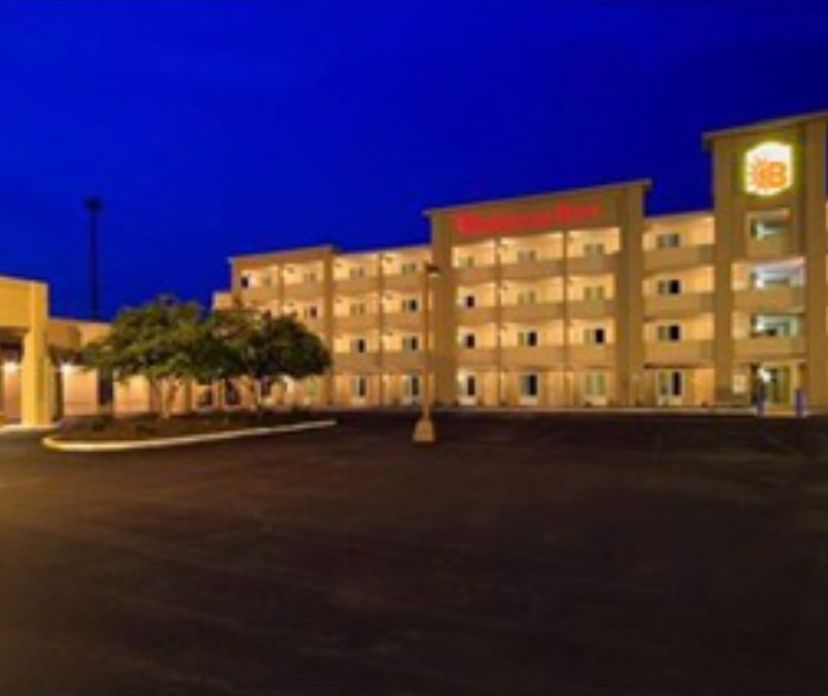 Exterior of a Super 8 motel at dusk with a dark blue sky and parking lot.