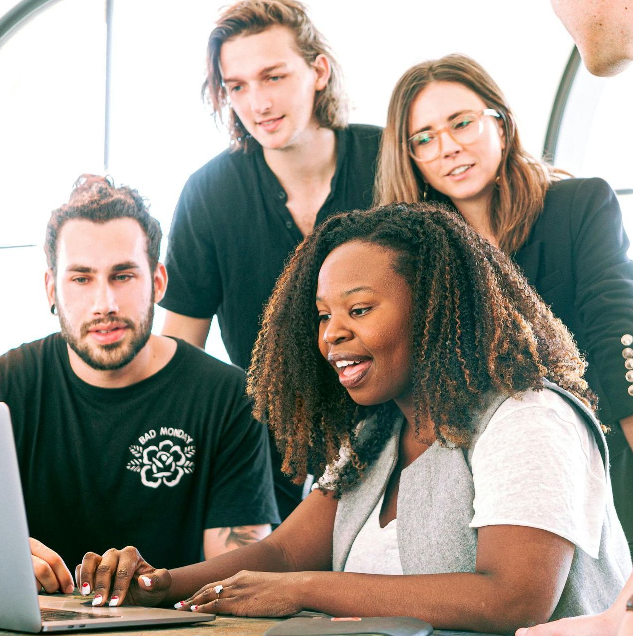 A group of people are looking at a laptop together