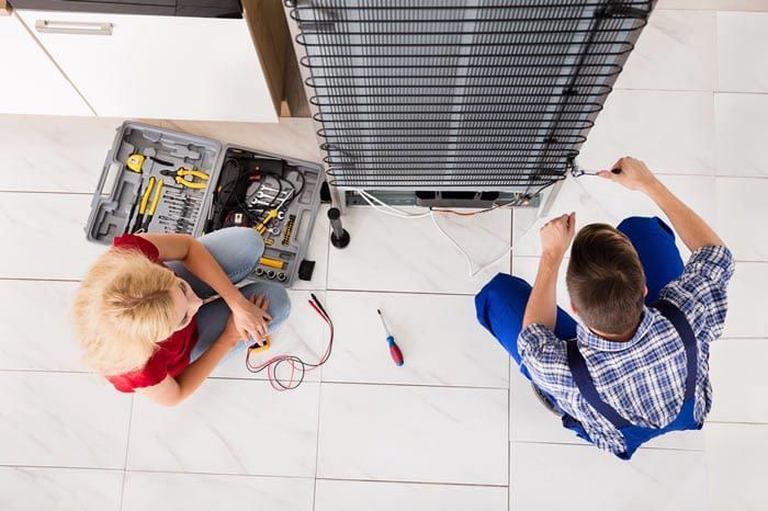 man repairing a refrigerator