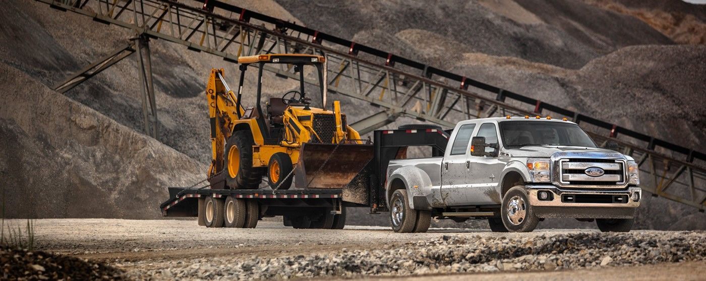 A truck is towing a bulldozer on a trailer.