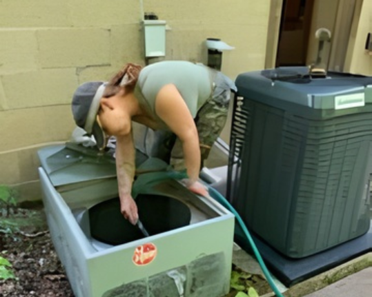 Person cleaning an air conditioning unit with a hose outdoors.